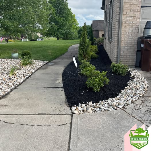 Black mulch bed with clean rock border by JW Landscaping