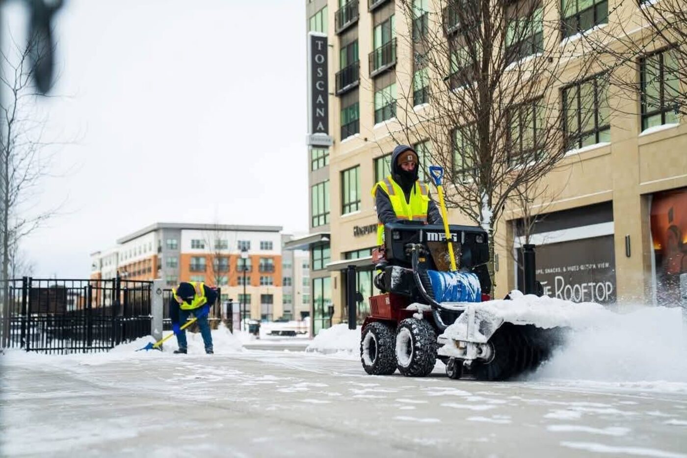 JW Landscaping crew clearing snow from a commercial sidewalk and plaza in Northern Kentucky